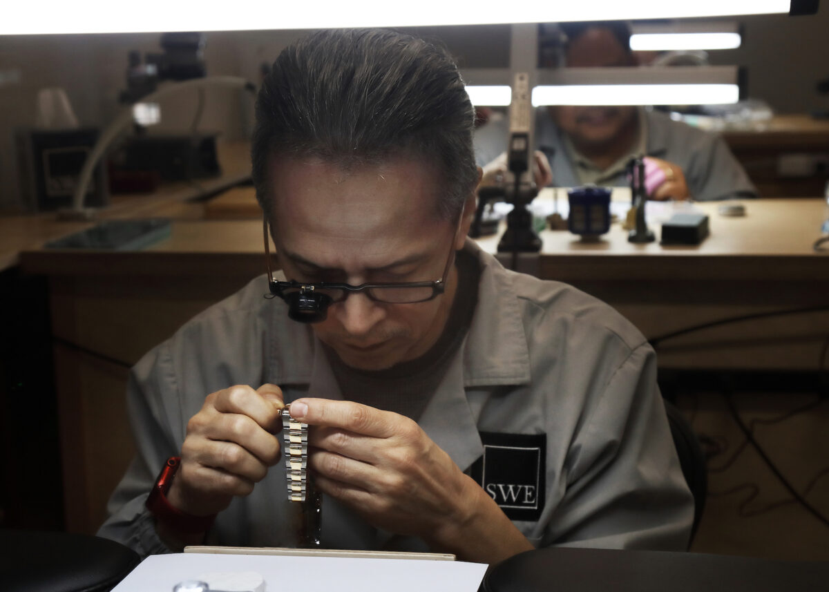 A professionally-trained watchmaker inspects a Rolex watch